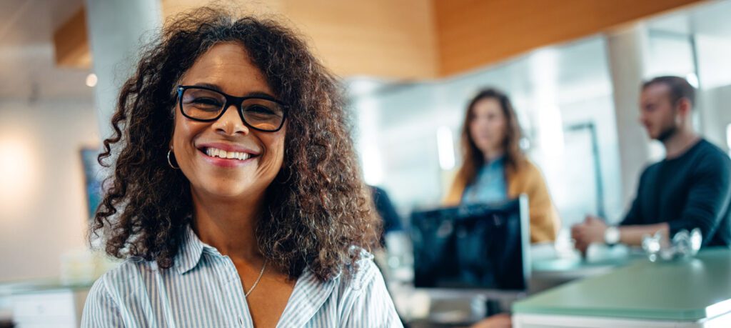 Woman smiling at the camera as she works in an office.