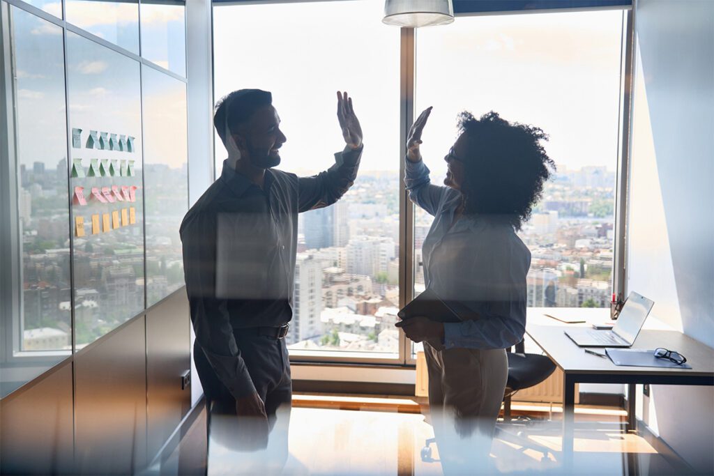 Two co-workers high-fiving in an office building.