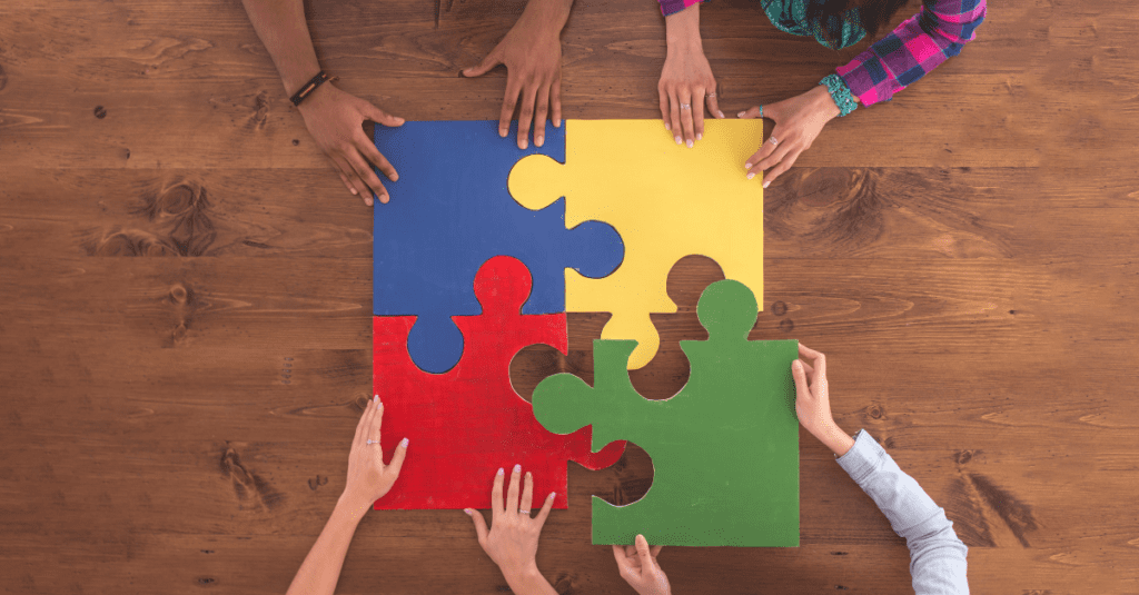 A diverse group of people fitting together oversized puzzle pieces.